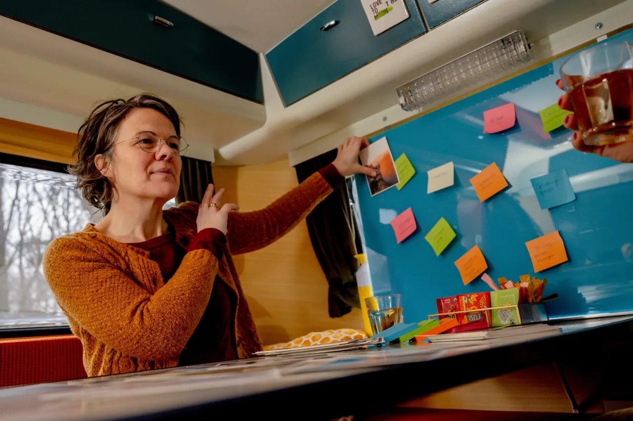 Ester houd een kaart tegen een bord met notities aan