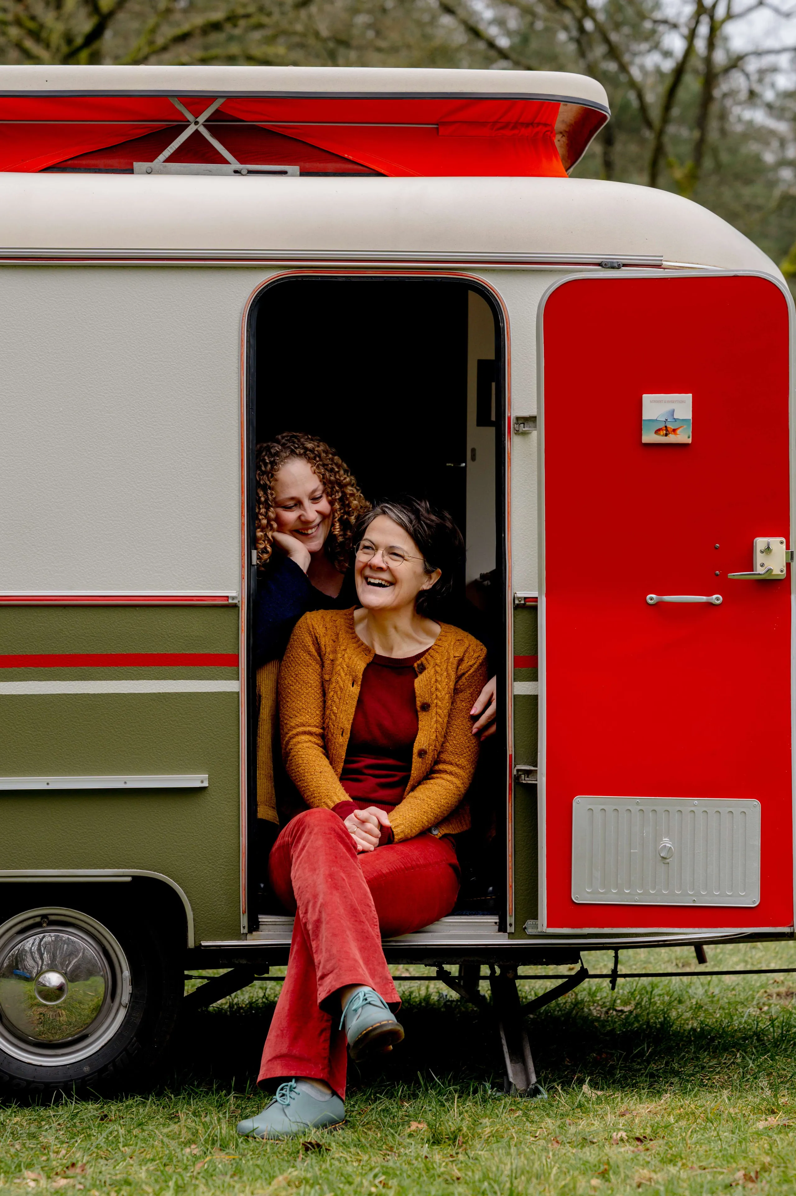 Niki en Ester zitten in de deuropening van hun caravan
