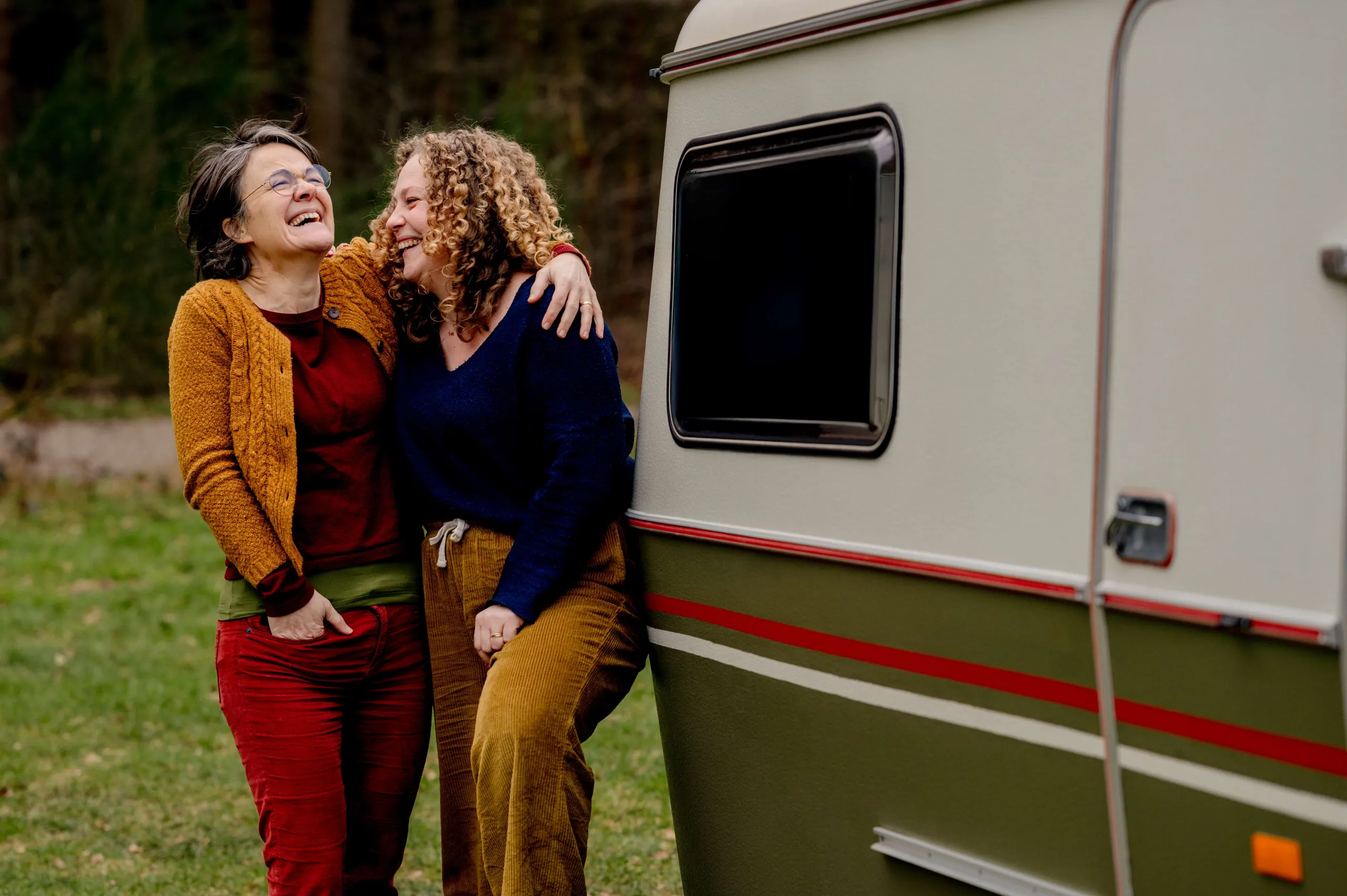Ester en Niki staan samen te lachen bij de caravan van Boven Kamers