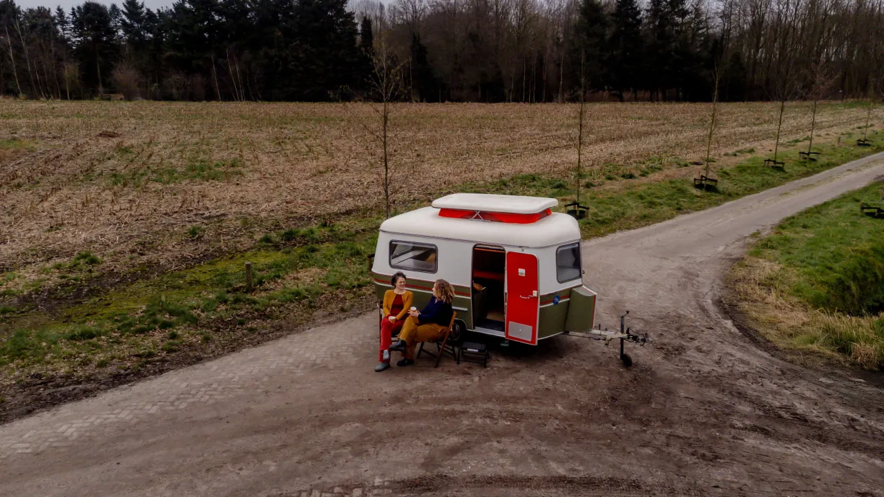 Ester en Niki drinken koffie voor de caravan