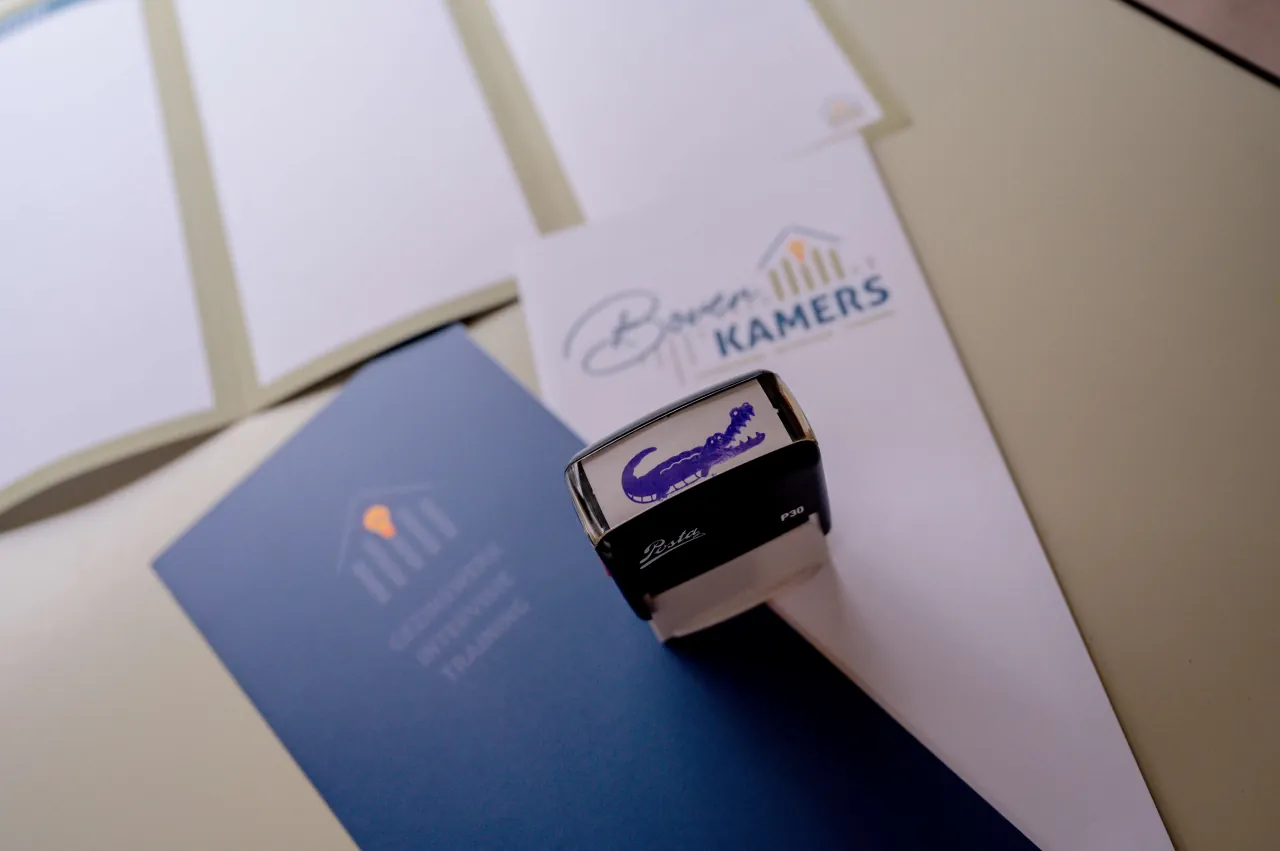 Een stempel met een krokodil bovenop flyers van Boven Kamers