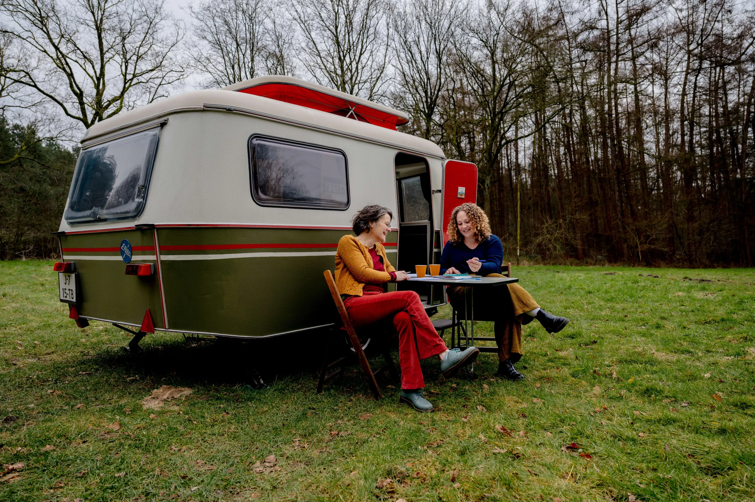 Ester en Niki zitten voor hun caravan aan tafel