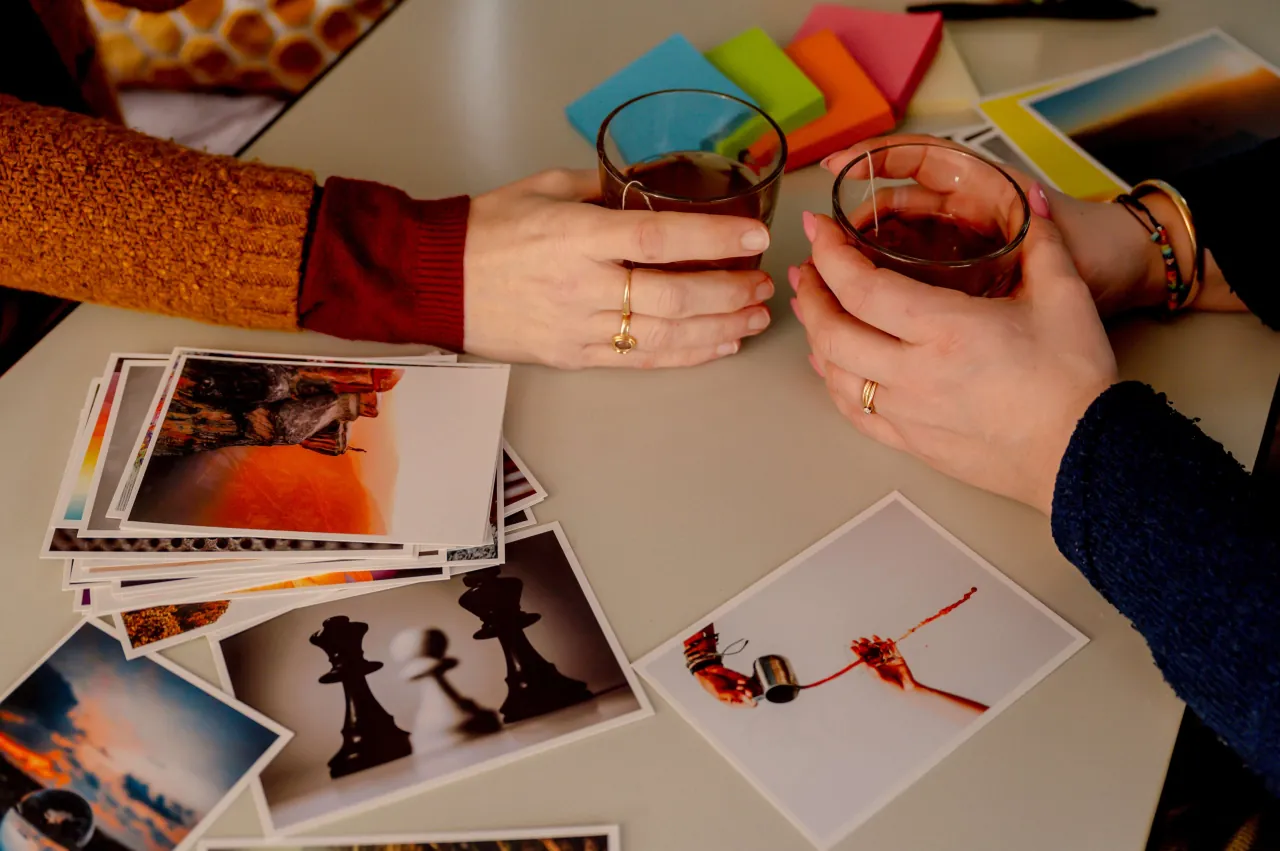 Een tafel met foto's en 2 personen die een kop thee vast houden